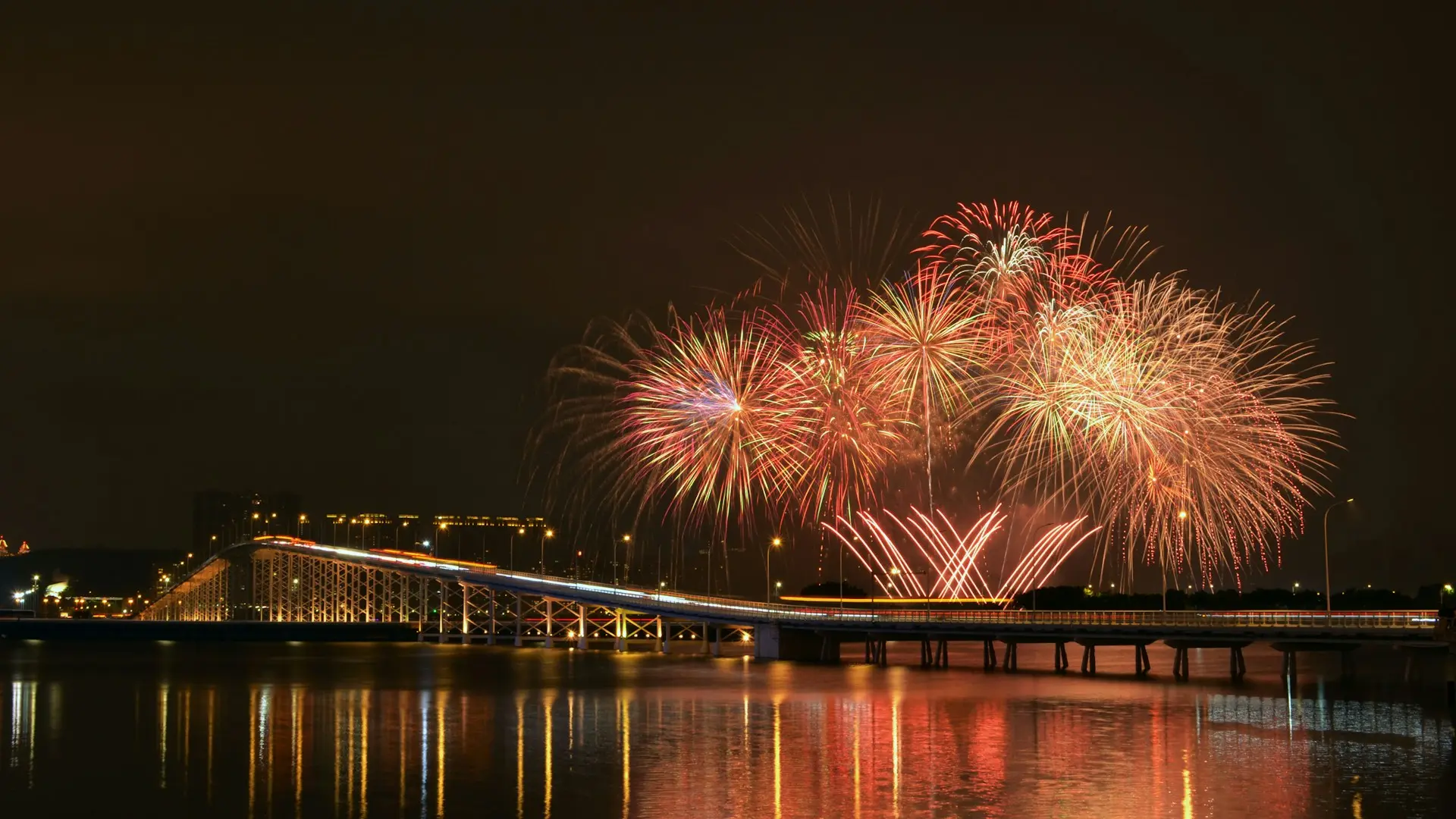 fireworks behind a bridge over water