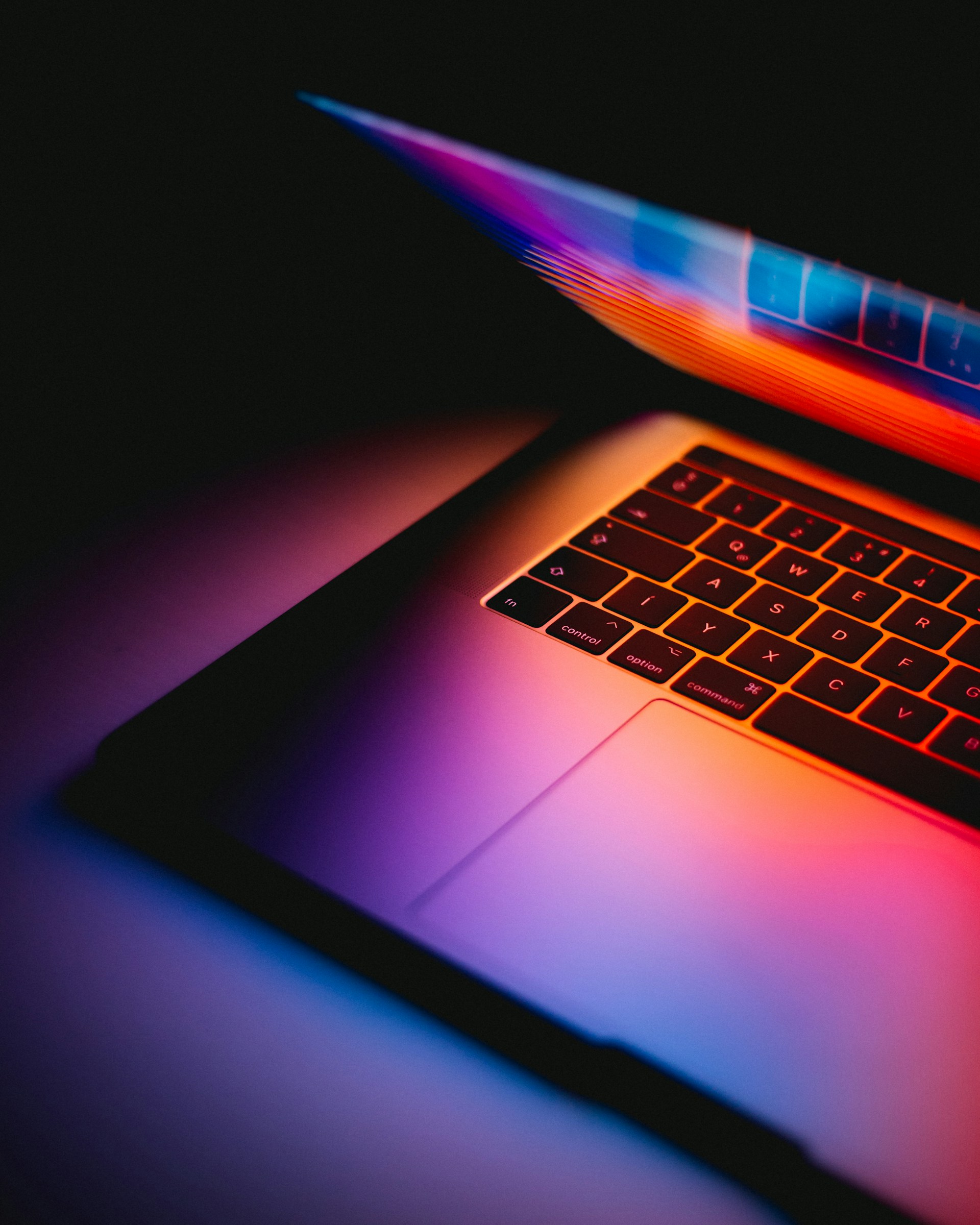 a macbook keyboard lit by a partially closed screen