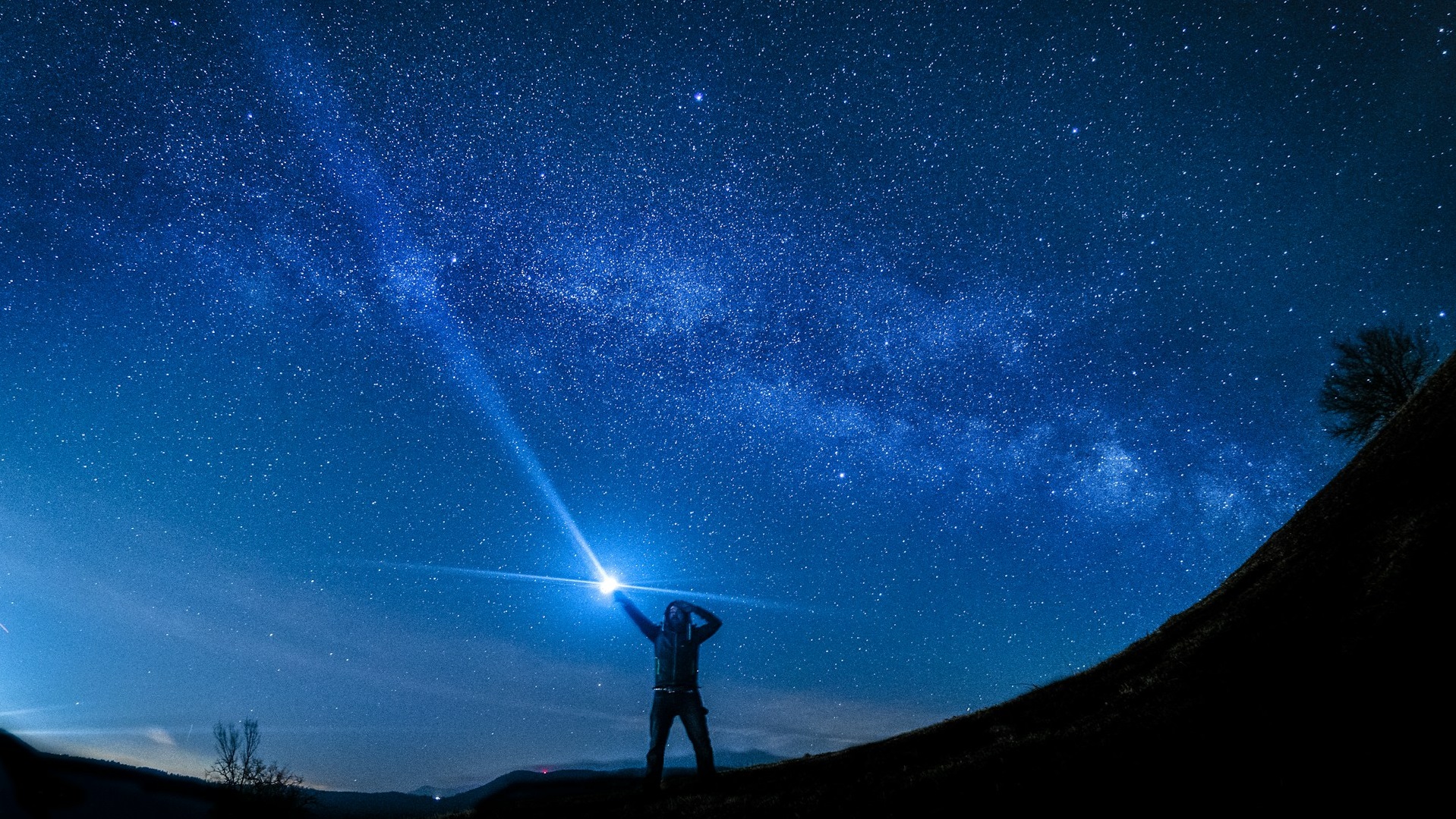 a man shining a flashlight in the night sky